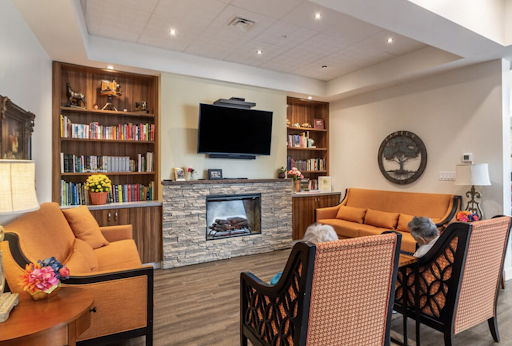 A cozy living room featuring a modern fireplace, built-in bookshelves, and comfortable orange seating.