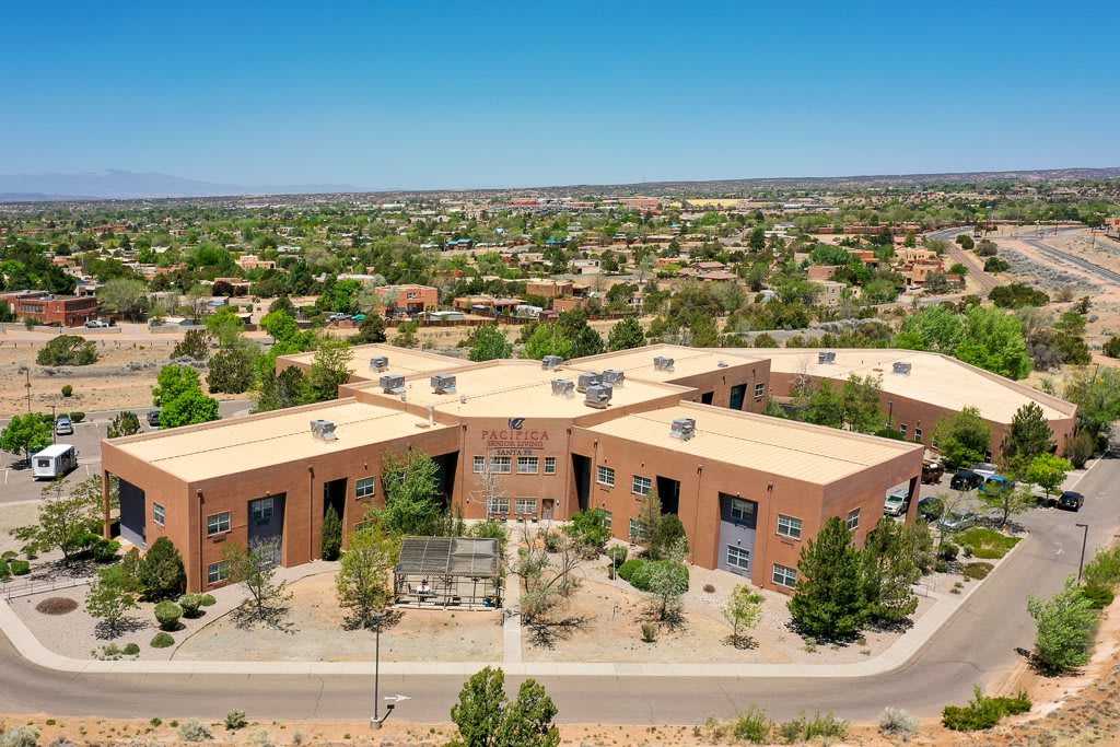 Aerial view of a complex of modern buildings surrounded by trees in a suburban area.