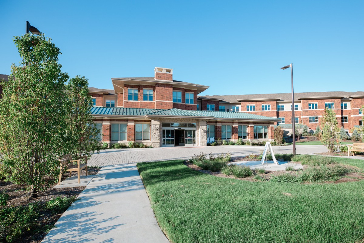 A modern building exterior with a landscaped pathway and clear blue sky.