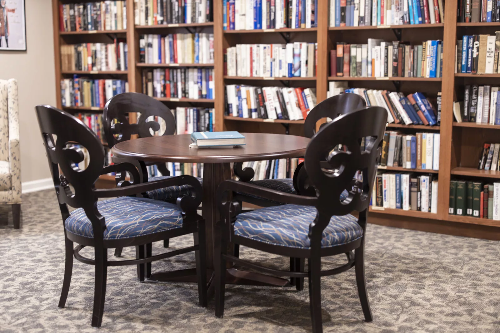 A cozy reading area with a round table and chairs surrounded by shelves filled with books.