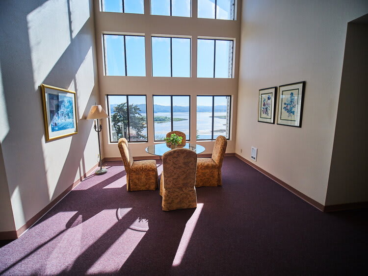 A bright and spacious room with large windows offering a stunning ocean view and a cozy dining area.