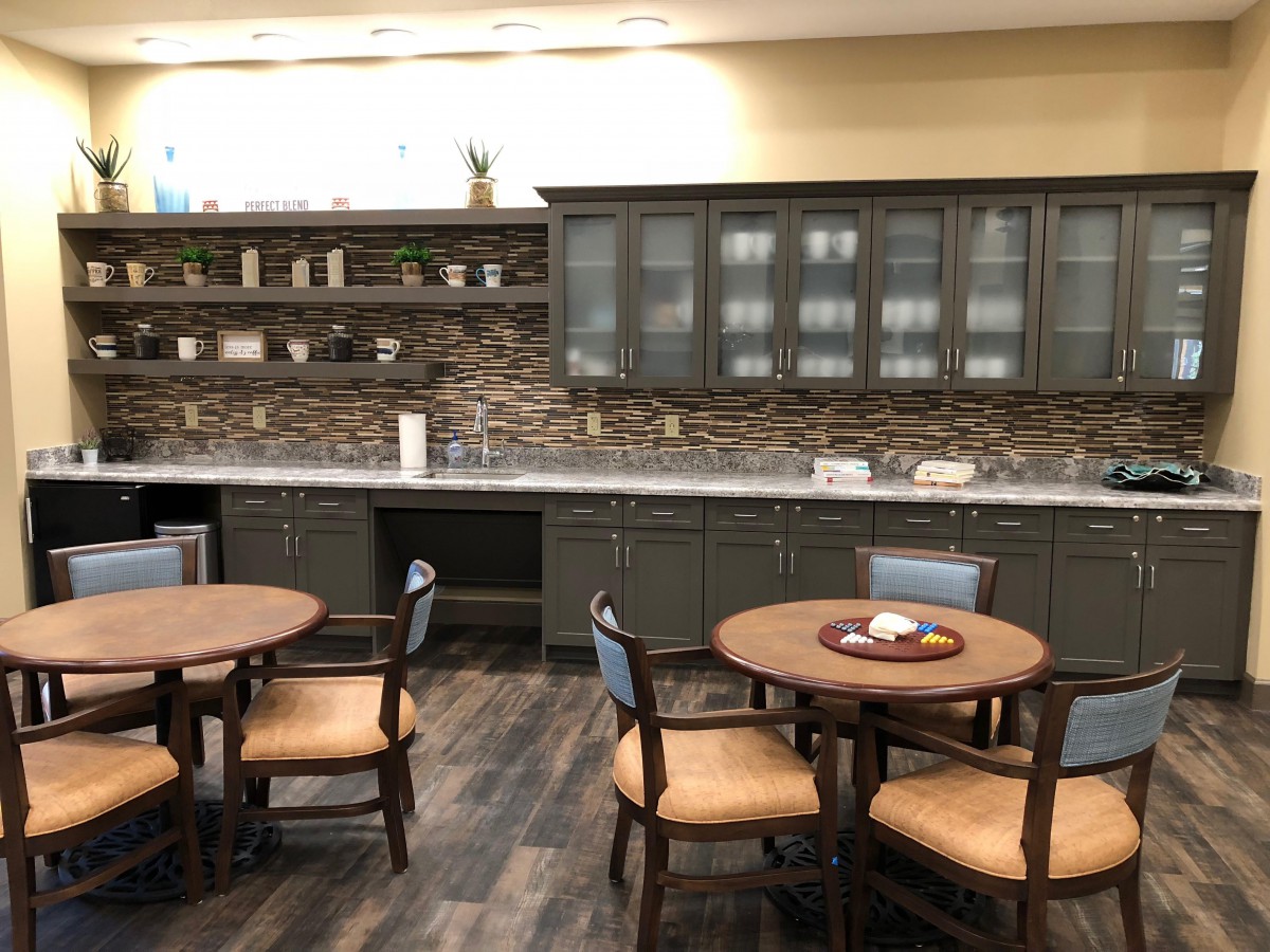 A modern kitchen and dining area with round tables and wooden cabinets.