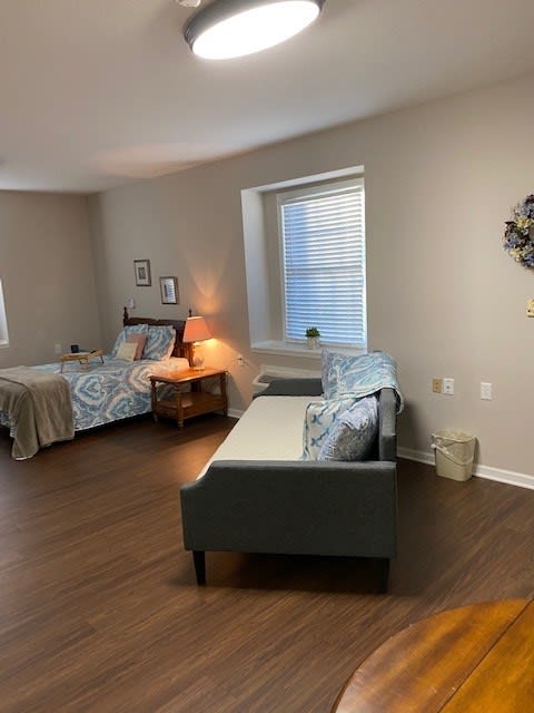 A cozy bedroom with two beds, a nightstand, and a lamp by the window.