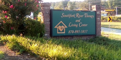 Signage for the Southfork River Therapeutic and Living Center surrounded by greenery.
