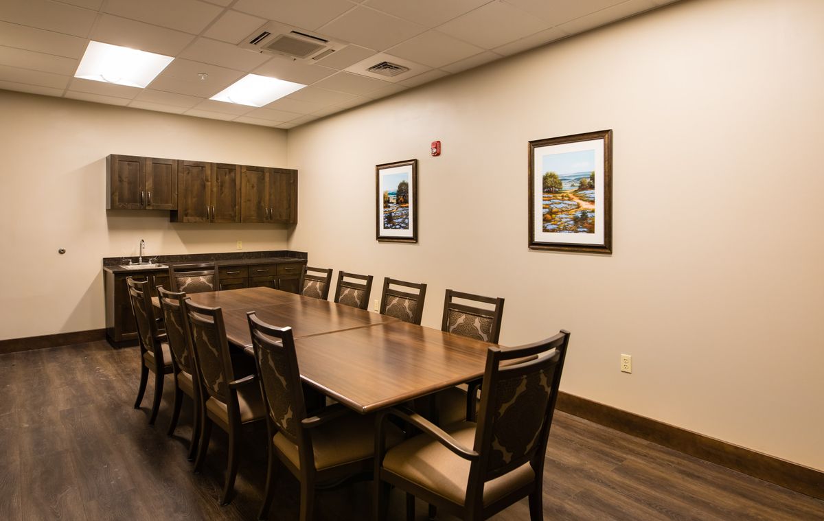 A well-organized conference room with a large table and chairs, featuring framed artwork on the walls.