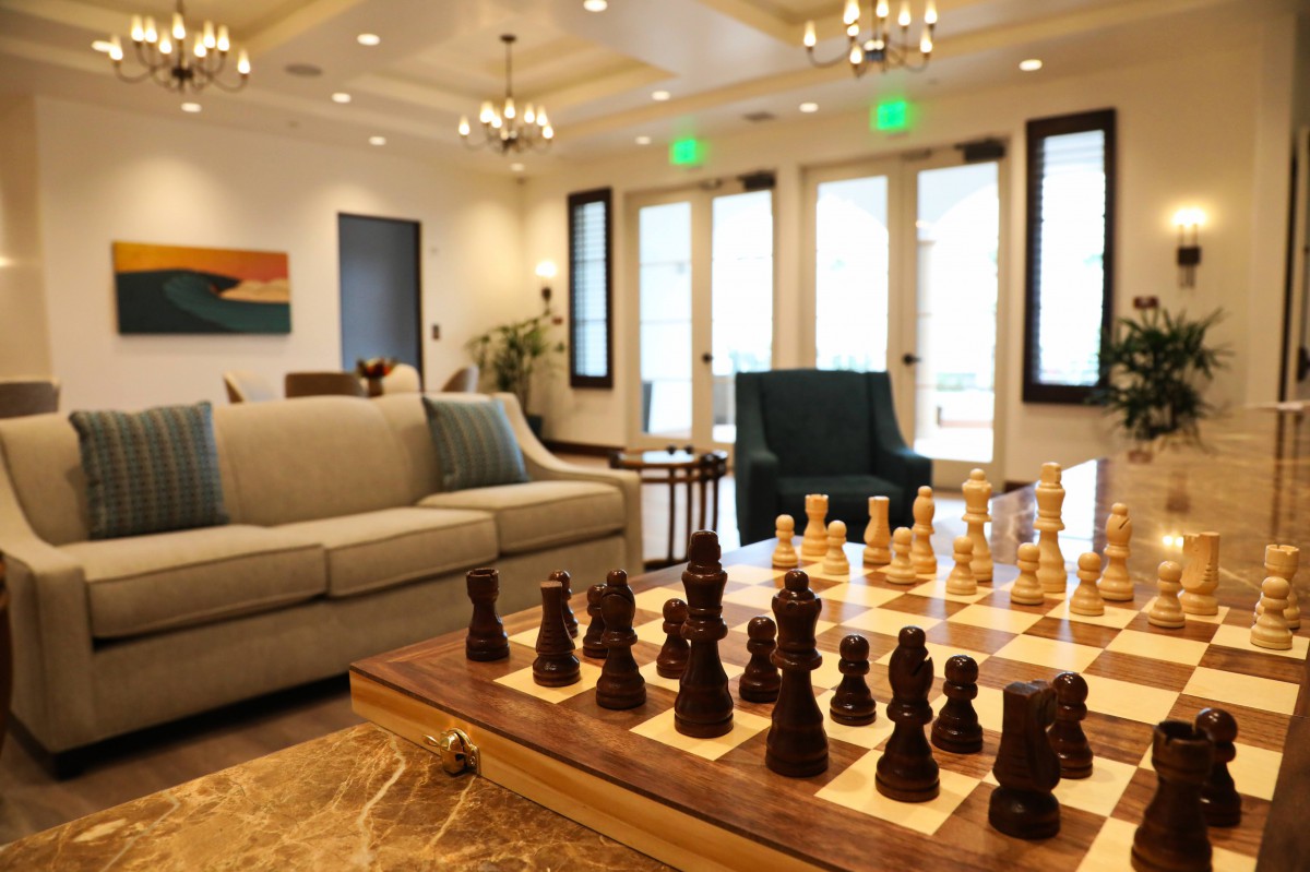 A cozy living room featuring a large chess board on a table, surrounded by comfortable seating and elegant lighting.