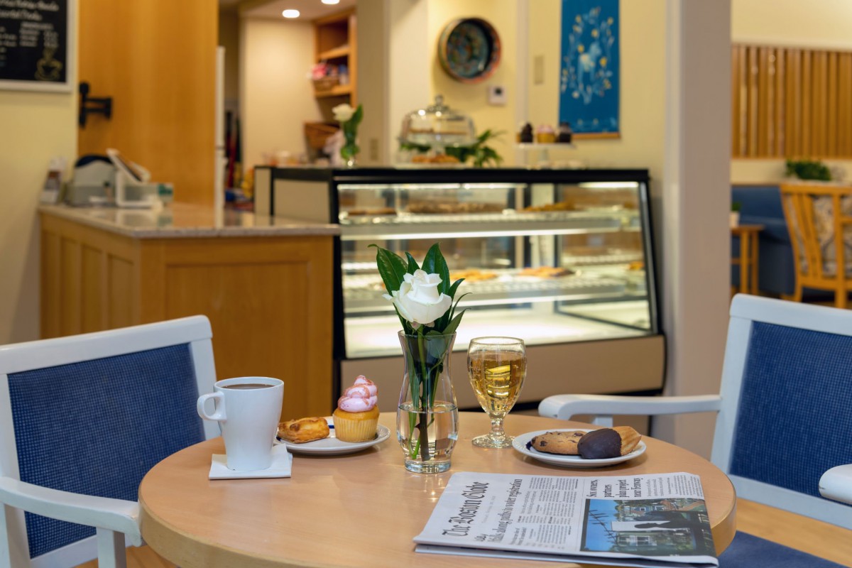 A cozy cafe table with pastries, coffee, and a newspaper.