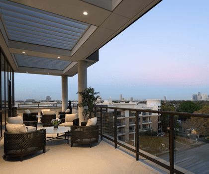 A modern balcony with comfortable seating offers a stunning city view at sunset.