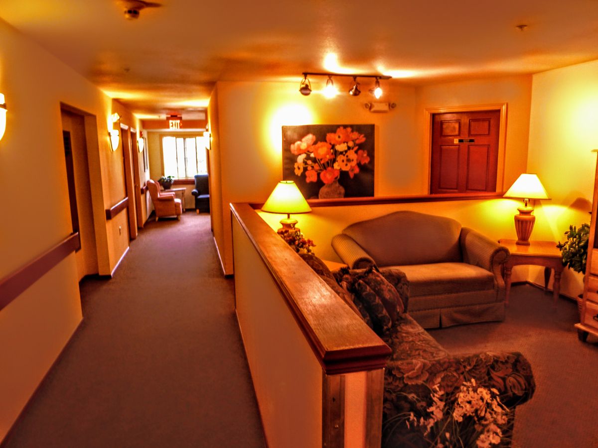 A cozy hallway with warm lighting and a seating area adorned with artwork.