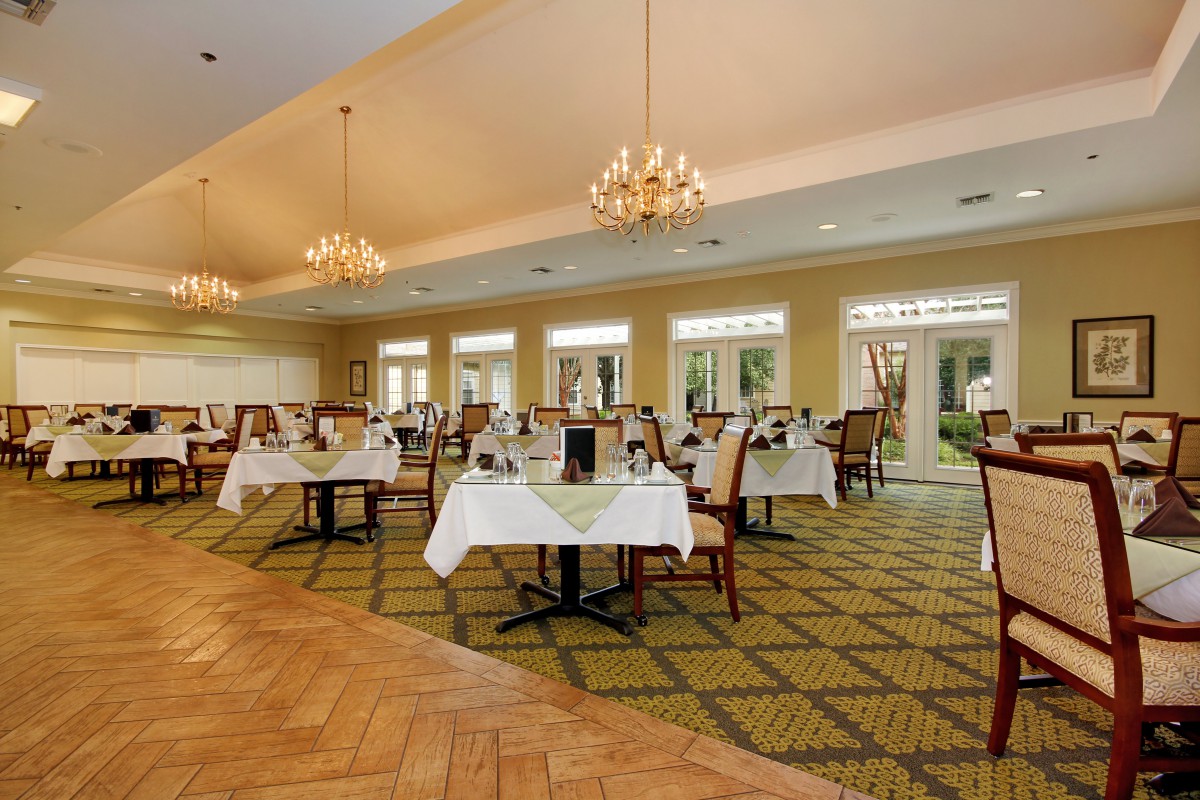 An elegant dining room with neatly arranged tables and chandeliers.