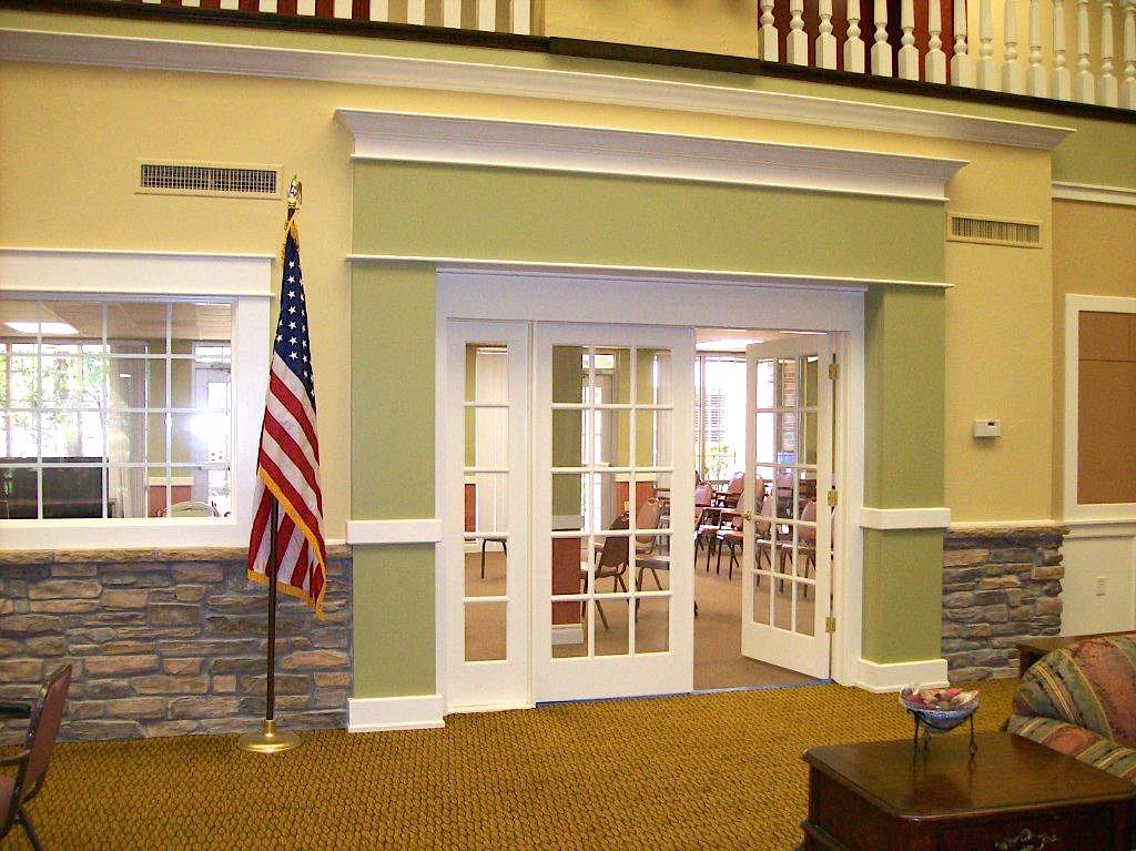 An interior view of a building entrance with glass doors and an American flag.