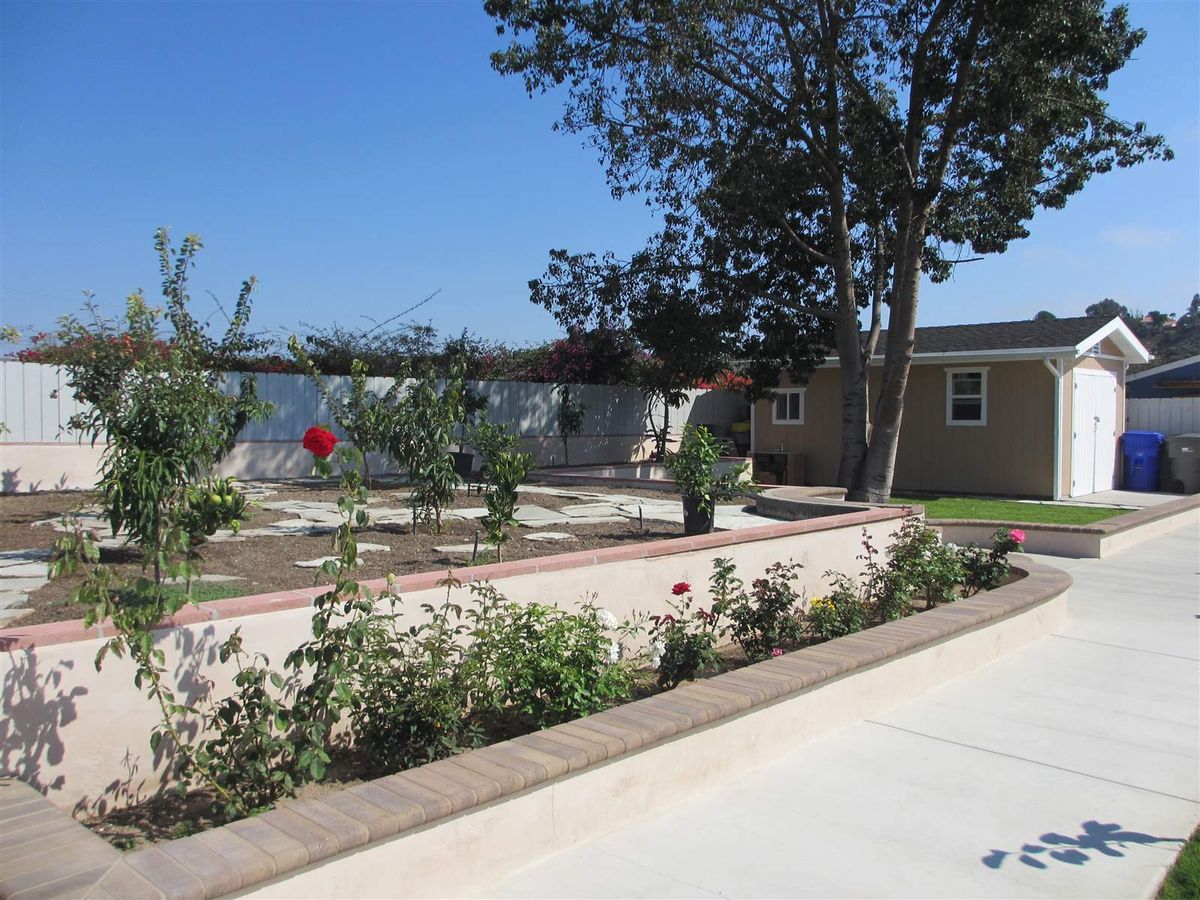 A landscaped garden with a pathway, surrounded by trees and plants next to a house.