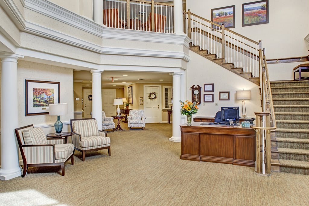 A beautifully designed lobby area featuring comfortable seating, a wooden reception desk, and an elegant staircase.