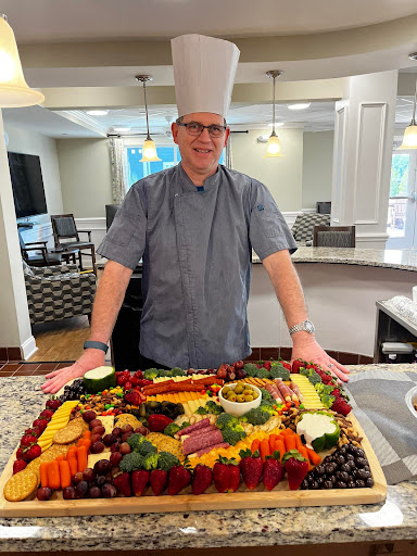 A talented chef showcasing a beautifully arranged fruit and cheese platter in a modern kitchen.