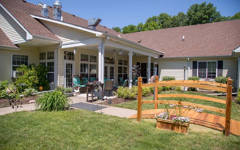 A sunny backyard with a patio and garden area, featuring a well-maintained lawn and outdoor seating.
