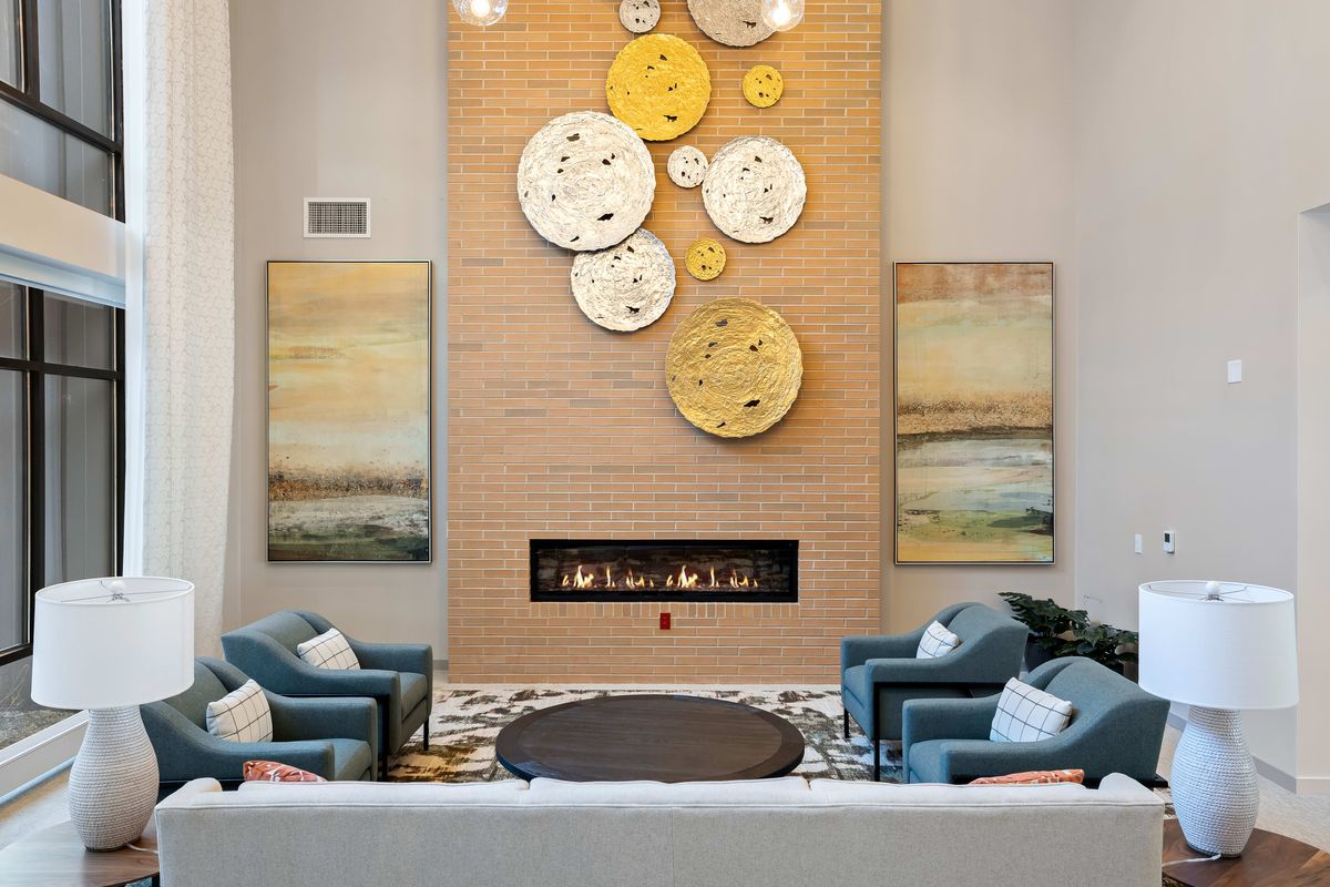 A modern living room with a cozy seating area and decorative wall clocks above a fireplace.
