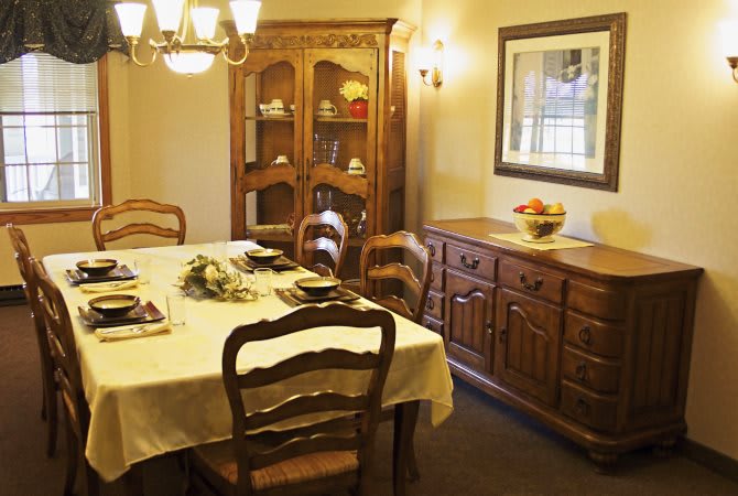 A cozy dining room with a traditional wooden dining table set, illuminated by a chandelier.