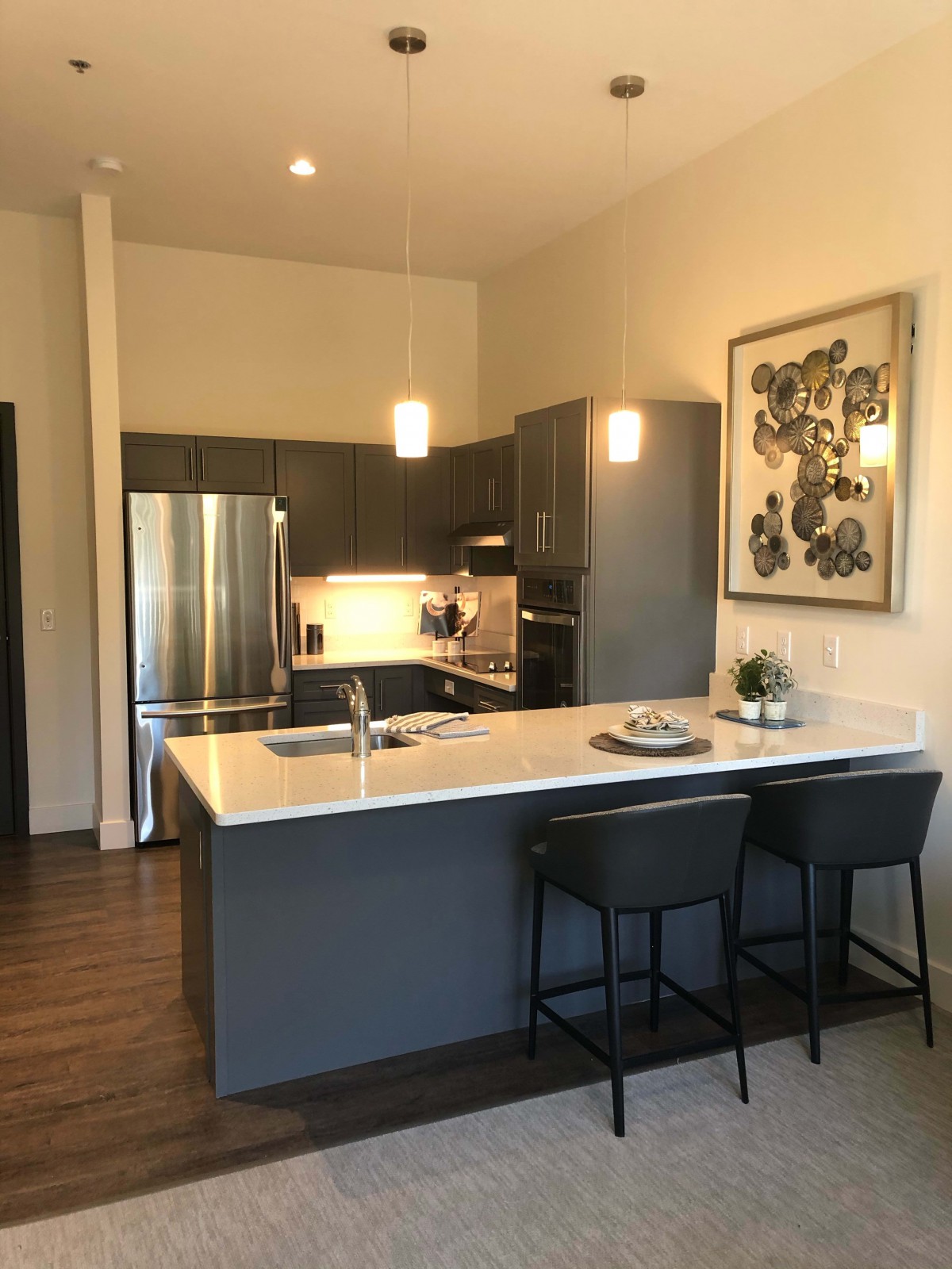 A modern kitchen with stainless steel appliances and bar seating in an apartment.