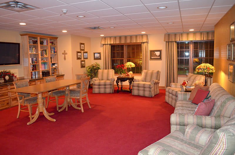 A cozy living room with red carpeting and comfortable seating arrangements.