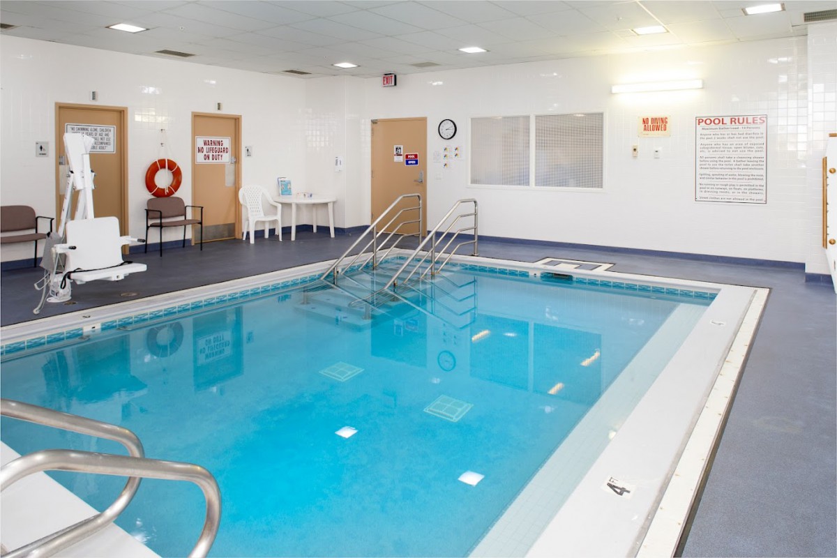 An indoor swimming pool area with safety equipment and seating.