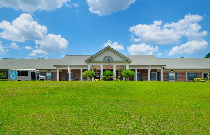 A large building with a porch under a blue sky with clouds.