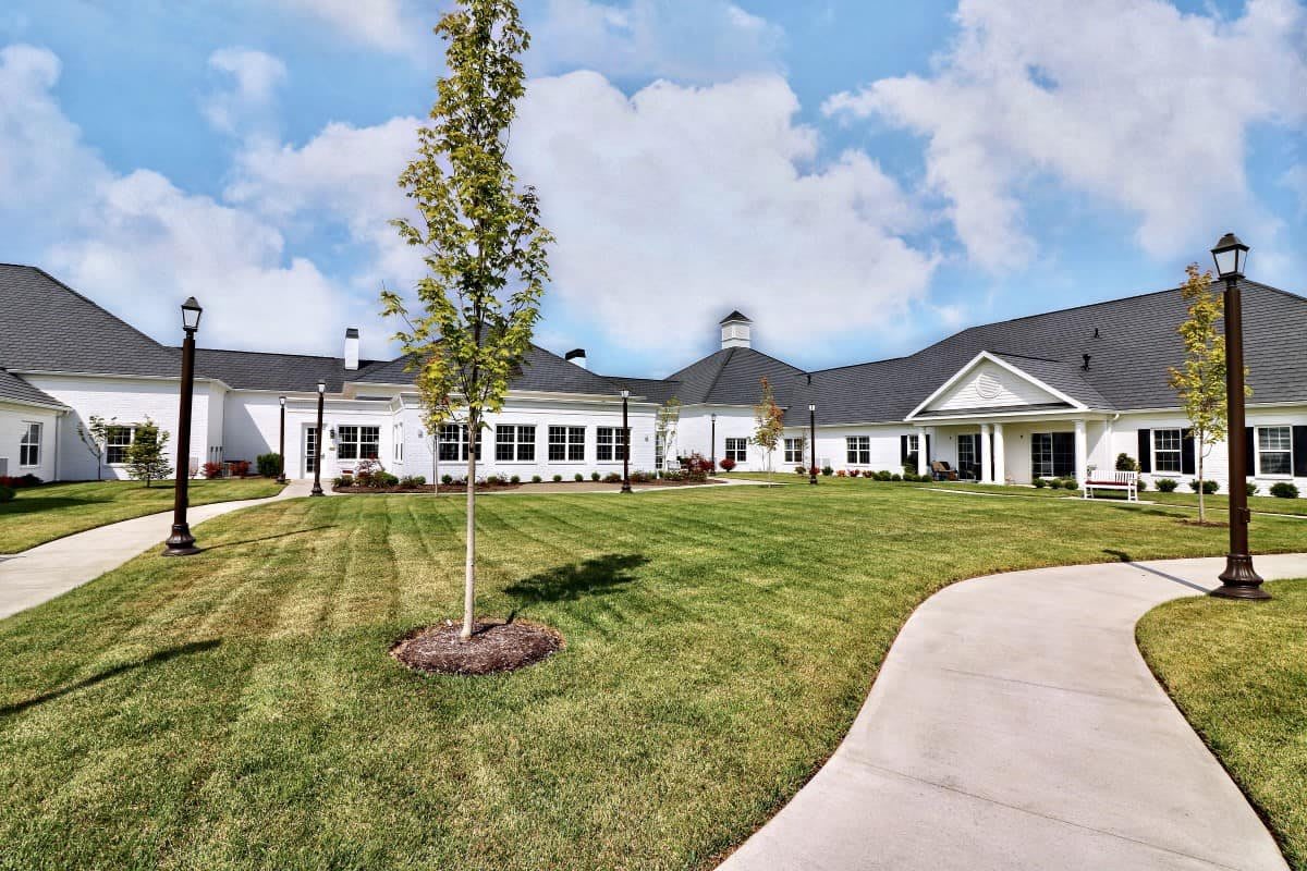 A modern building with a well-maintained lawn and landscaping under a cloudy sky.