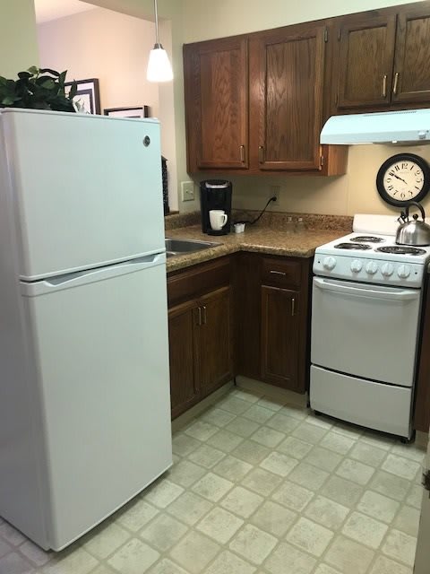 A compact kitchen with a refrigerator, stove, and coffee maker.
