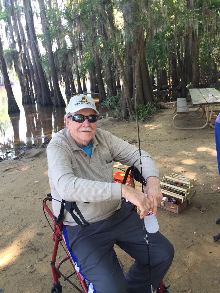 A person enjoying a peaceful day fishing by the river in a forested area.