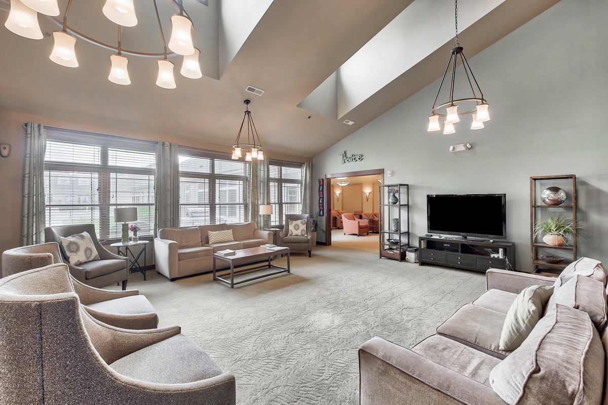A spacious and modern living room with large windows, stylish furniture, and elegant lighting.