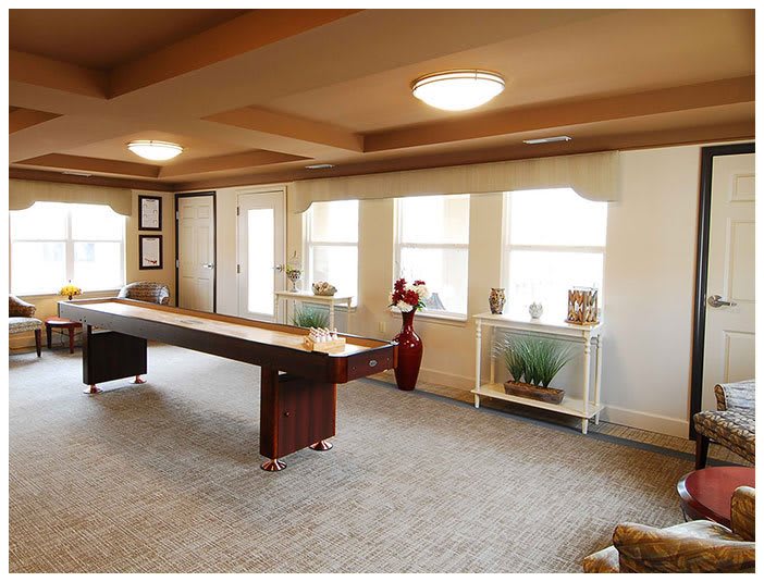 A spacious room with a long table, multiple windows, and warm lighting.