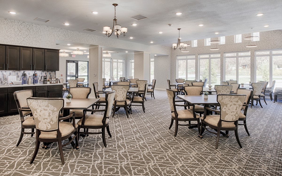 A well-lit dining room with elegant furniture and large windows.