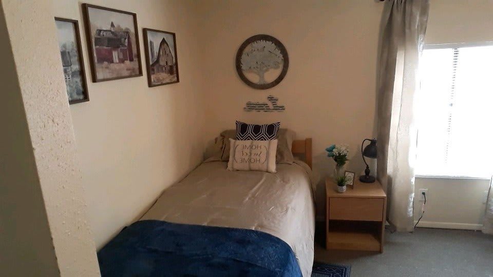 A cozy bedroom with a single bed, decorative pillows, and wall art.