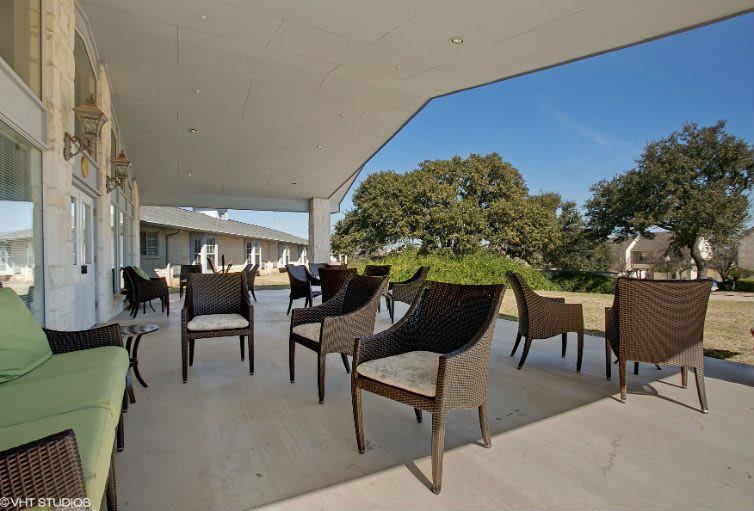 A modern outdoor patio with chairs overlooking lush greenery on a sunny day.