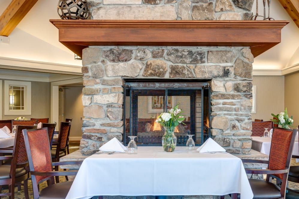 A cozy dining setup with a stone fireplace in the background, featuring a table set with flowers.