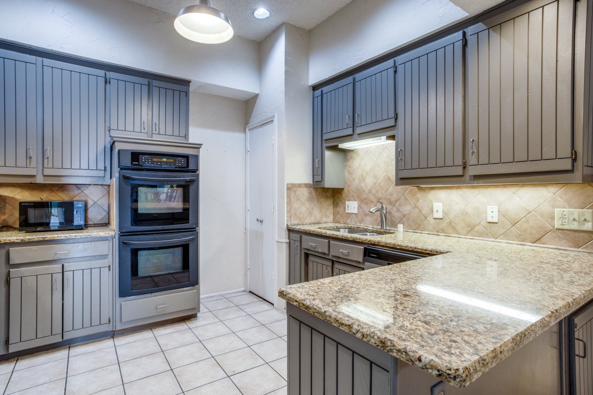 Modern kitchen with granite countertops and double oven.