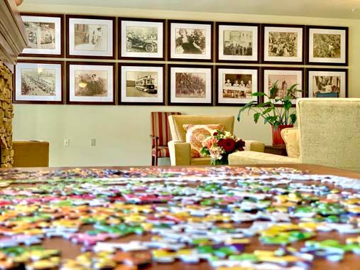 A lounge area with a colorful puzzle in the foreground and framed pictures on the wall.