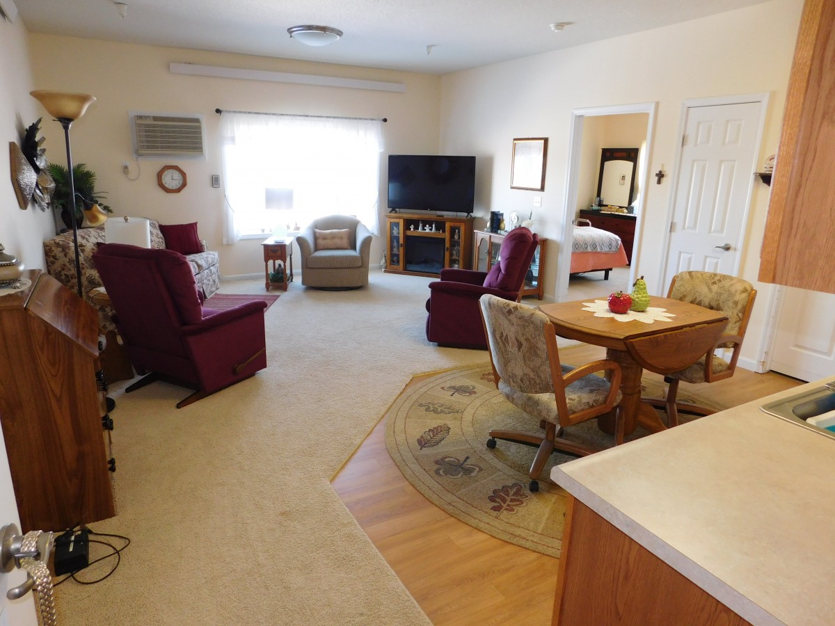 A cozy living room featuring a seating area with armchairs, a television, and home decor.