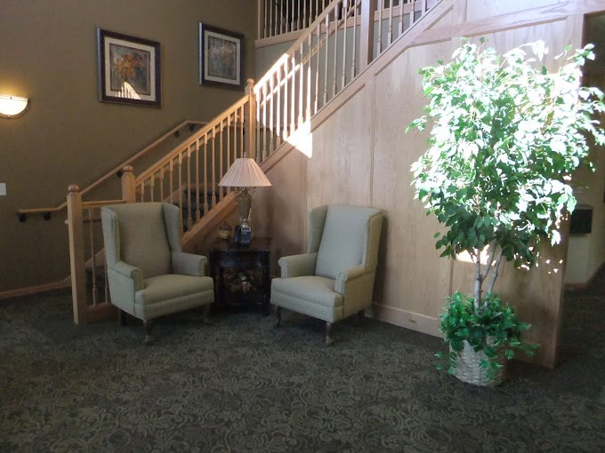 A cozy lobby area with two armchairs, a side table with a lamp, and a staircase in the background.