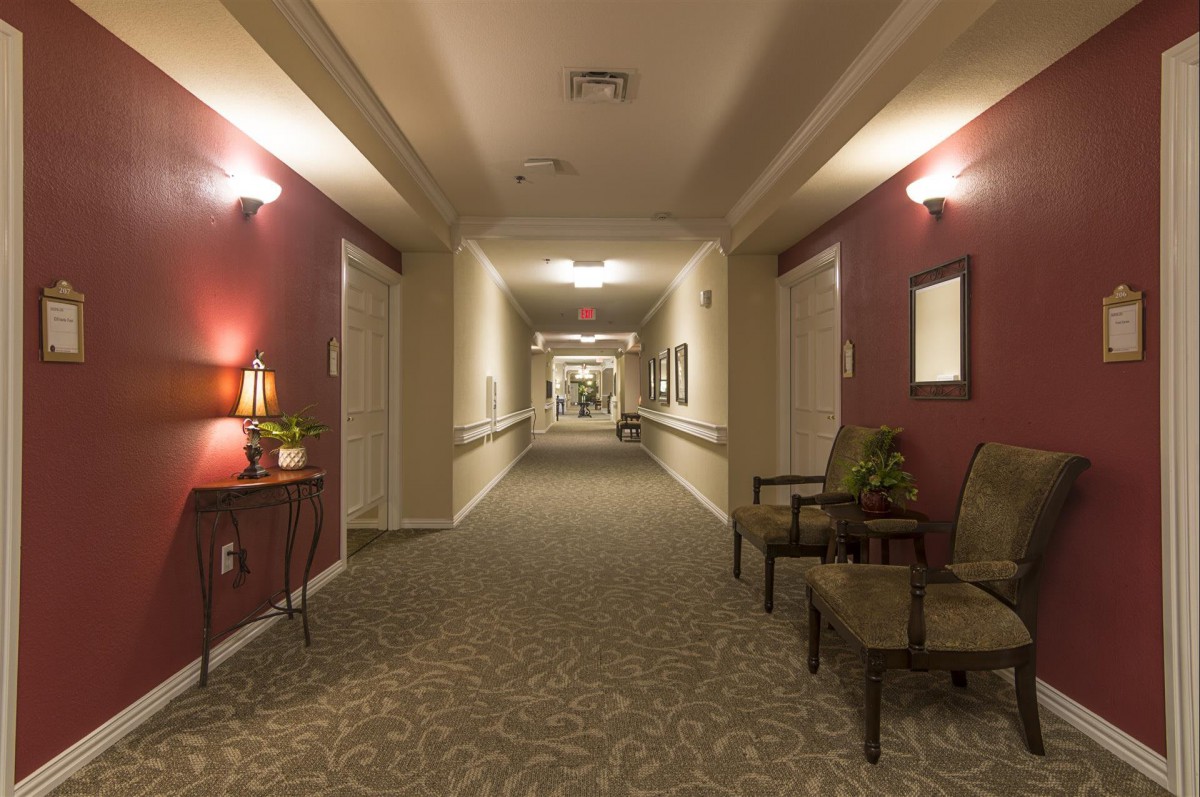 A well-lit, carpeted hallway with decorative elements including chairs and lamps.