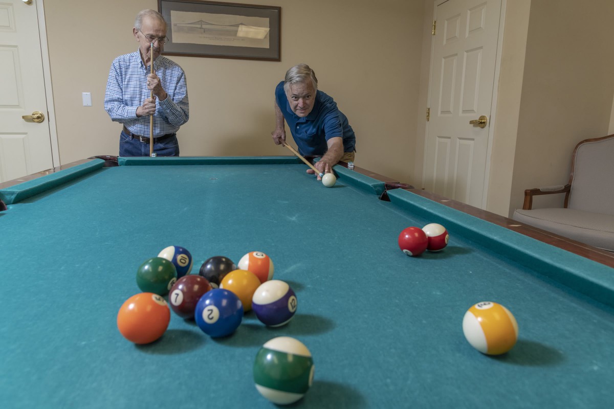Two people engaged in a friendly game of pool indoors.