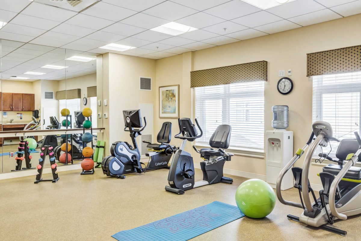 A well-equipped fitness room with stationary bikes, an exercise ball, a yoga mat, and other gym accessories.