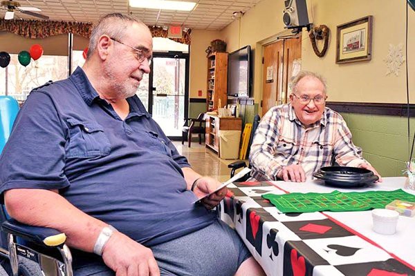 Two senior men enjoying a game at a table, smiling in a relaxed indoor setting.