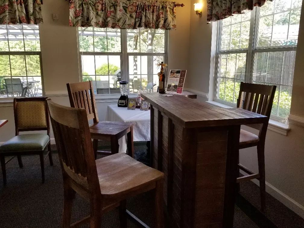 A cozy dining room with wooden furniture and large windows.