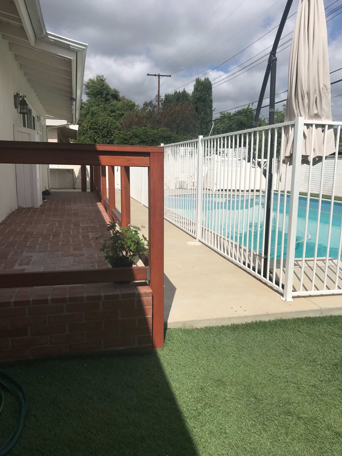 A sunny backyard with a swimming pool and a fenced-off area.