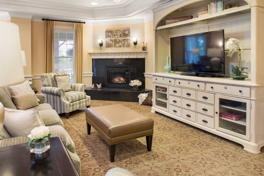 A cozy living room with a fireplace, armchairs, and a television set.