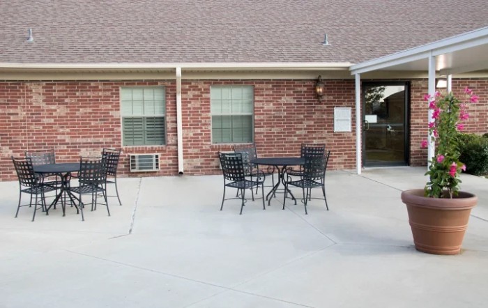 An outdoor patio area with metal tables and chairs in front of a brick building.