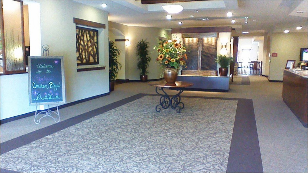 A hotel lobby with elegant decor, featuring elevators, decorative plants, and a central table.