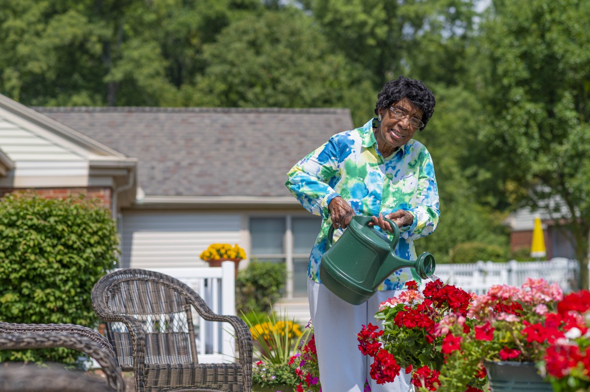 A woman enjoys watering her garden on a sunny day.