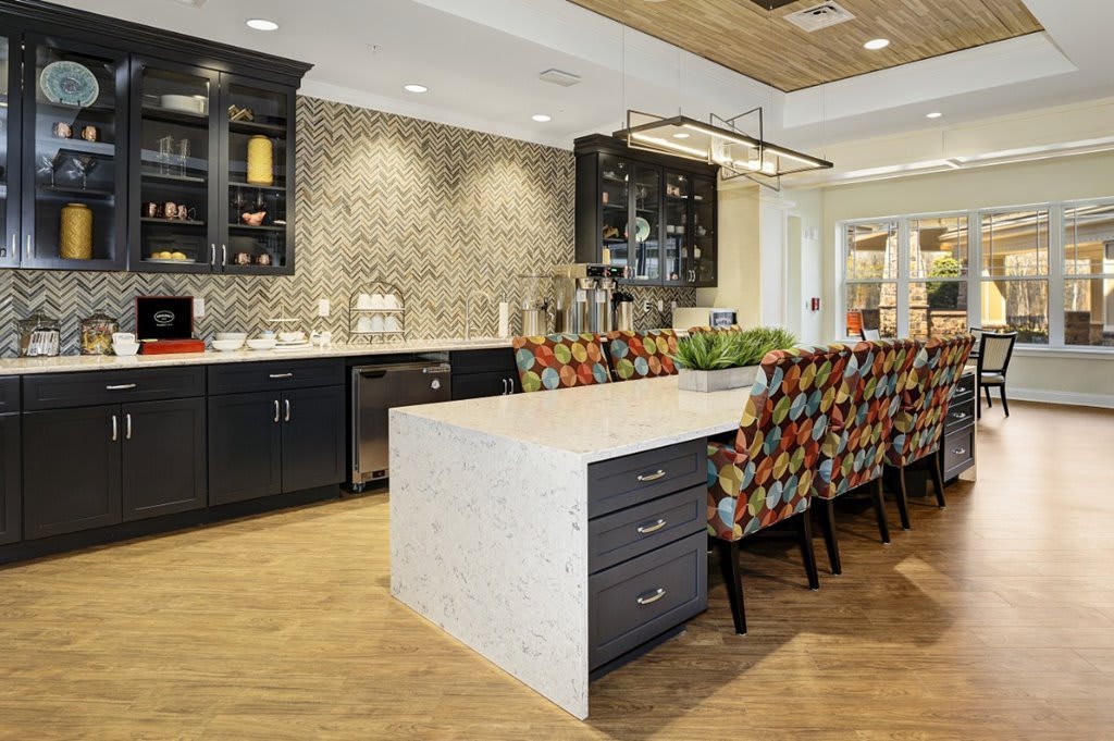 A modern kitchen with a large island, colorful bar stools, and sleek cabinetry.