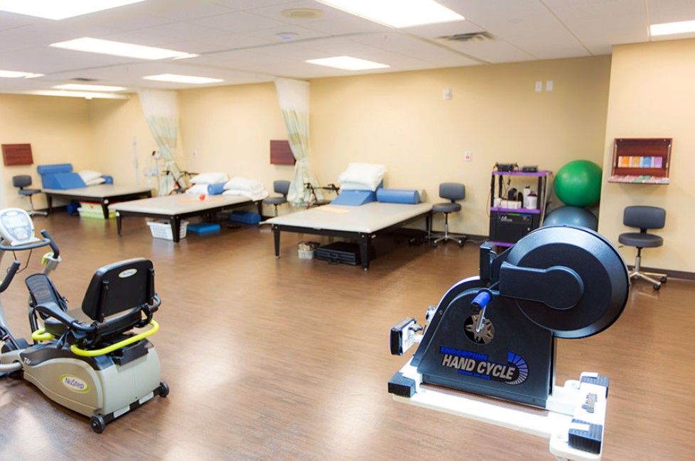 A physical therapy room equipped with exercise machines and treatment tables.